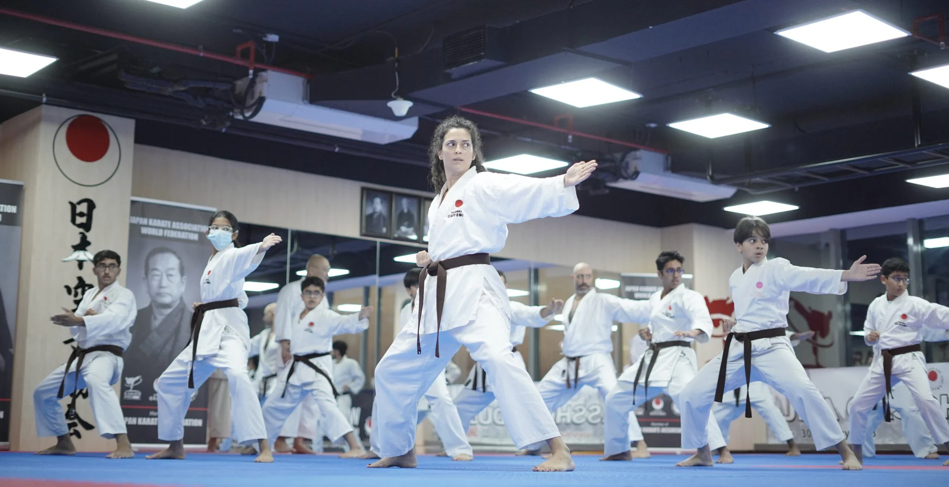 Students holding a front stance in rows during a karate class
