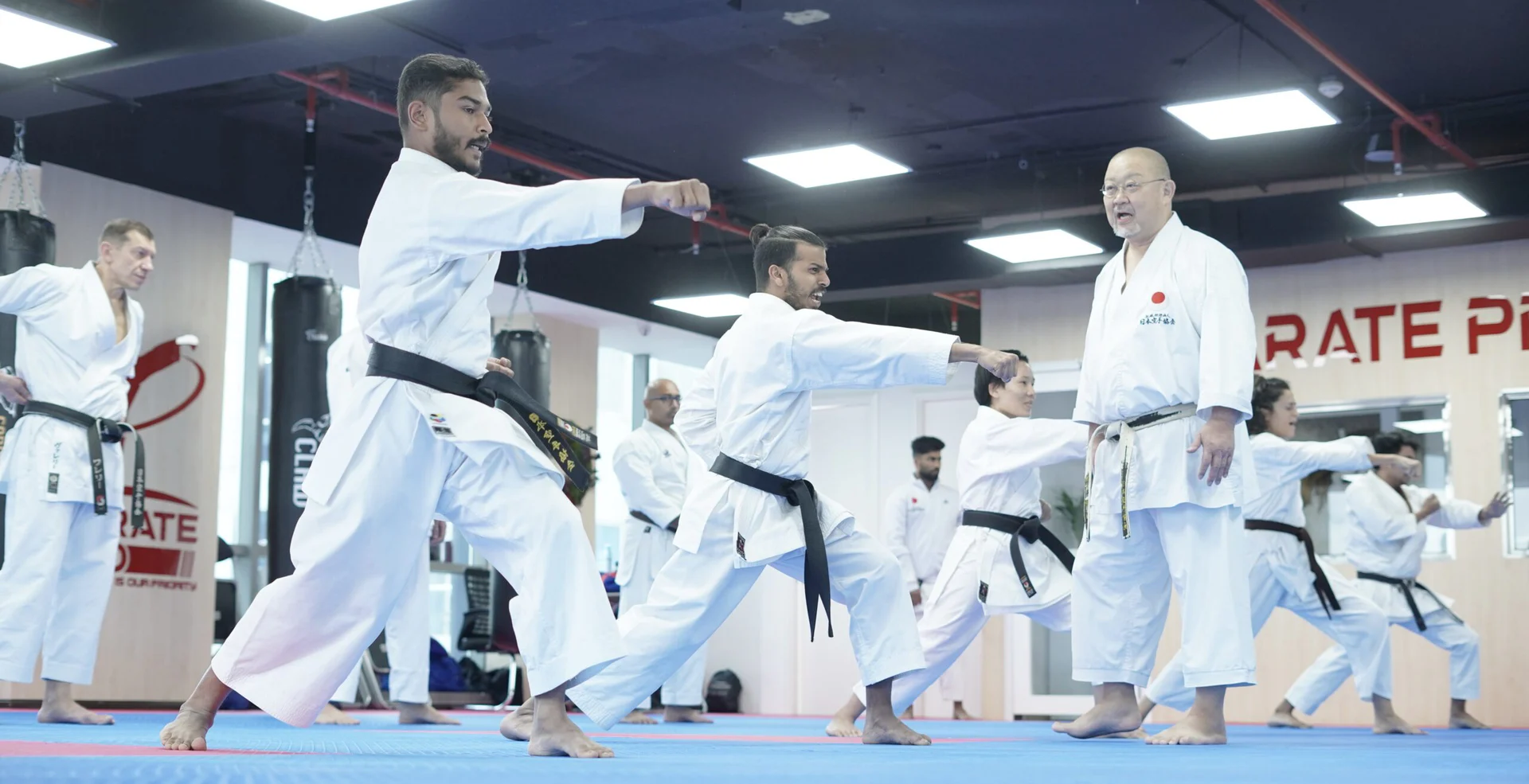 Black belt students practising a punching drill together on the blue mats