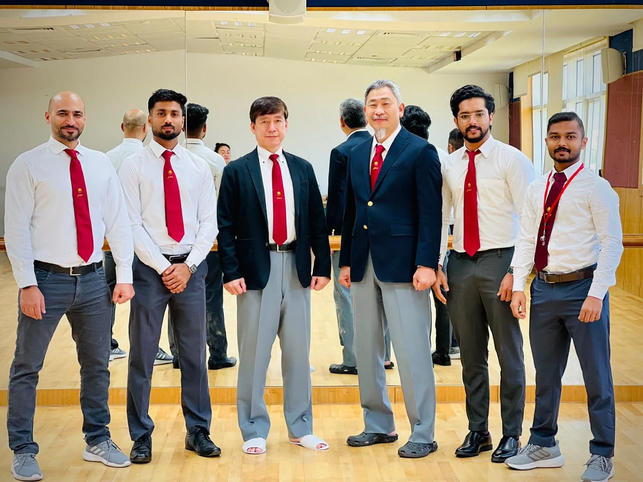 Karate Pro instructors in white shirts and red ties posing together indoors