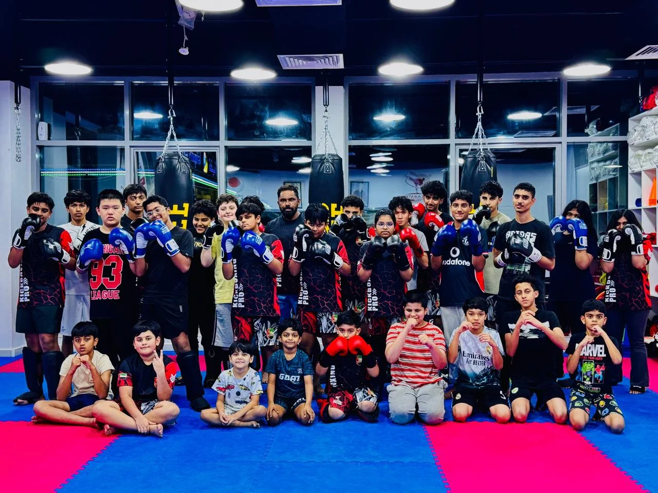 Kickboxing class and coaches posing together in gloves on the mats
