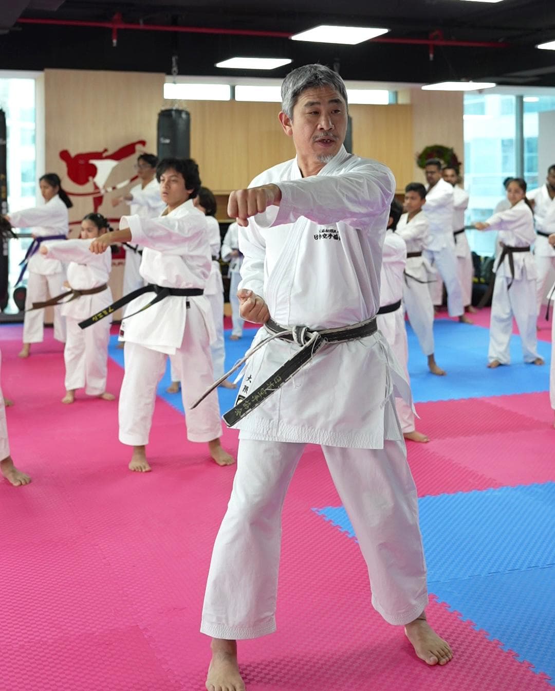 Senior instructor leading a punching drill with a class of adult karatekas