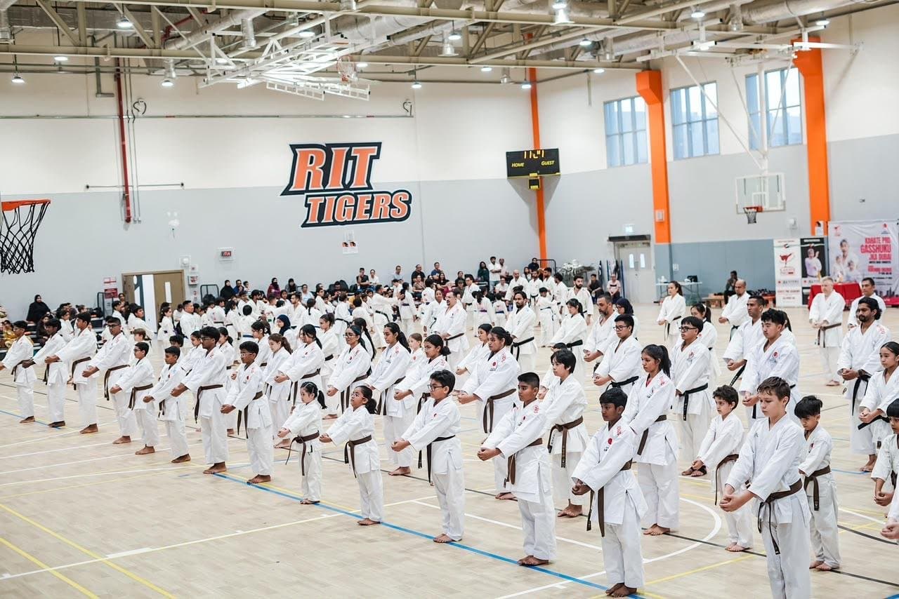 Rows of karatekas practising kata together at a JKA Gasshuku seminar in the RIT Dubai sports hall