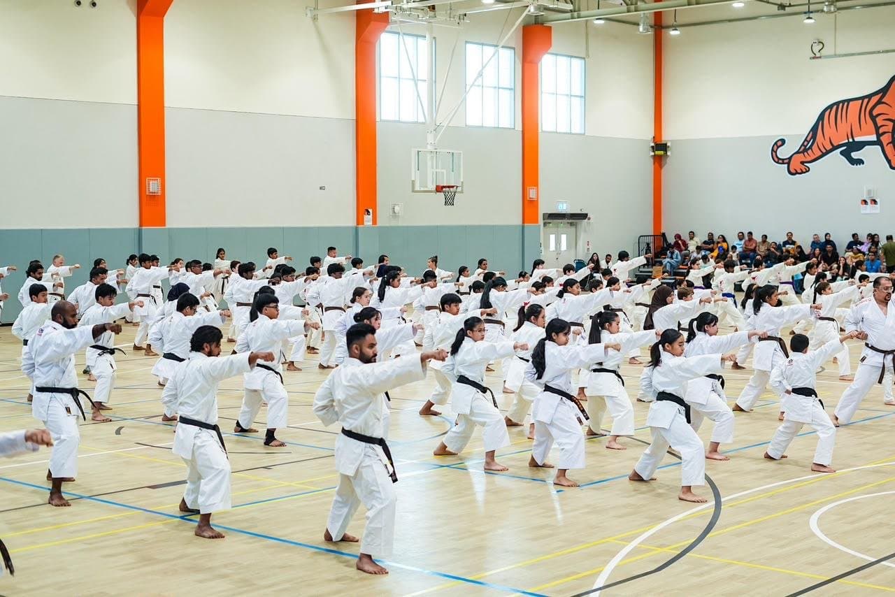 Rows of students practising a punching drill together at a JKA Gasshuku seminar in the RIT Dubai sports hall
