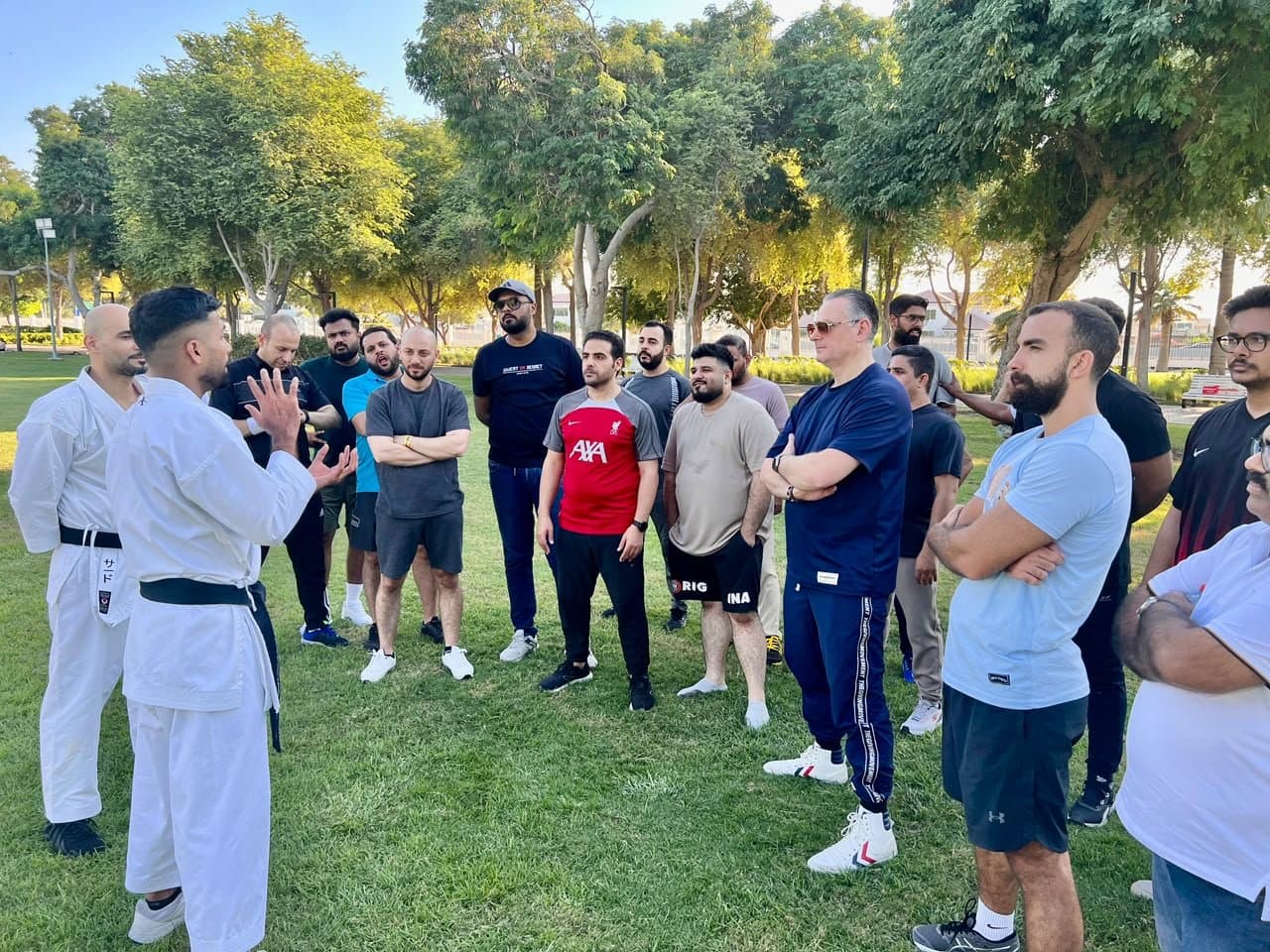 Instructor addressing a group of students gathered on the grass during an outdoor seminar in a Dubai park