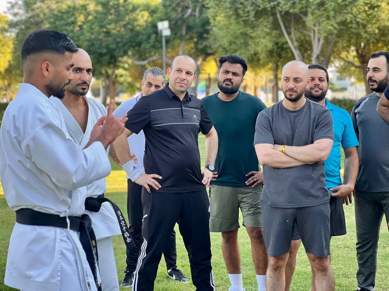 Black belt instructor speaking with a small group of students outdoors on the grass