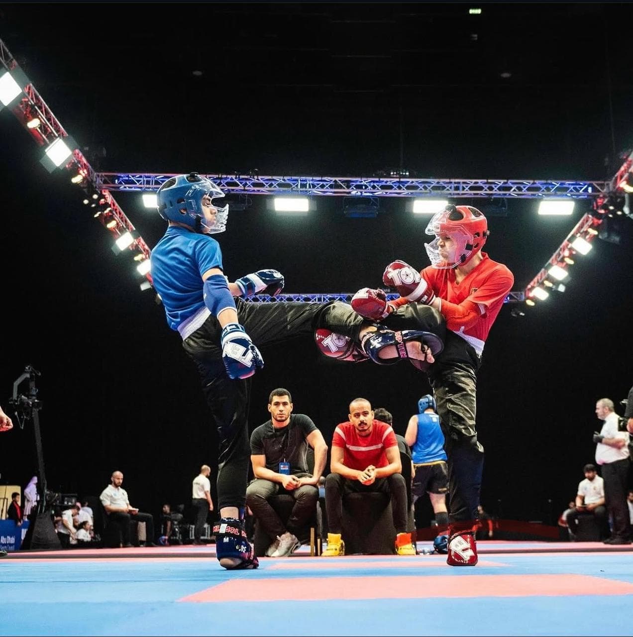Two junior kickboxers exchanging kicks in a ring at an indoor arena