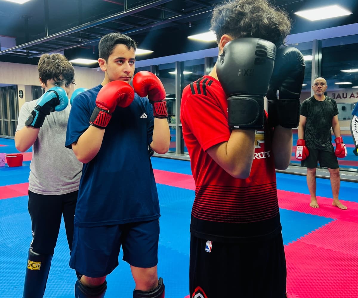Teenagers in gloves standing in guard position during a kickboxing class on red and blue mats