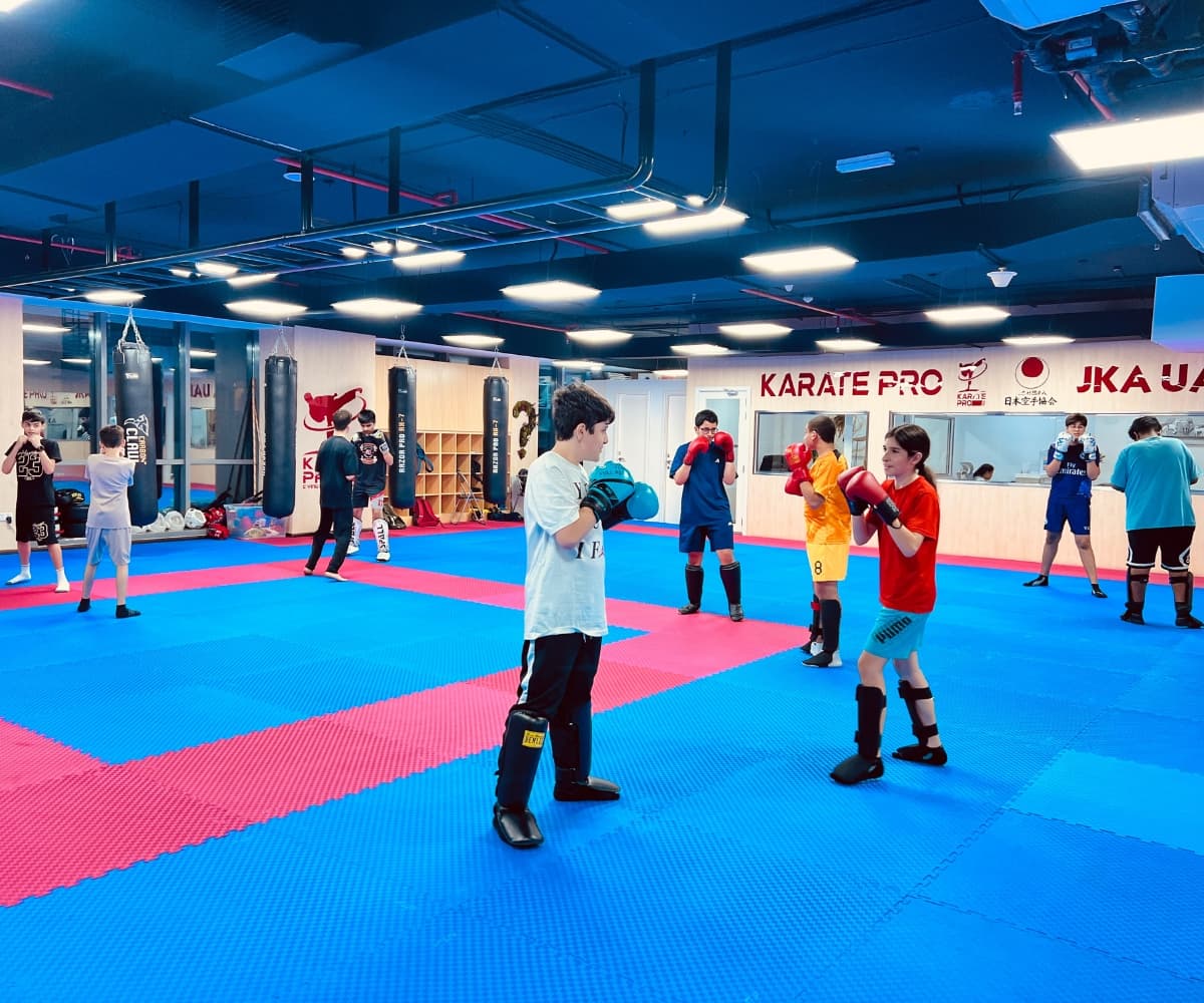 Kids and teens spread across the mats during a busy kickboxing class beneath the Karate Pro sign