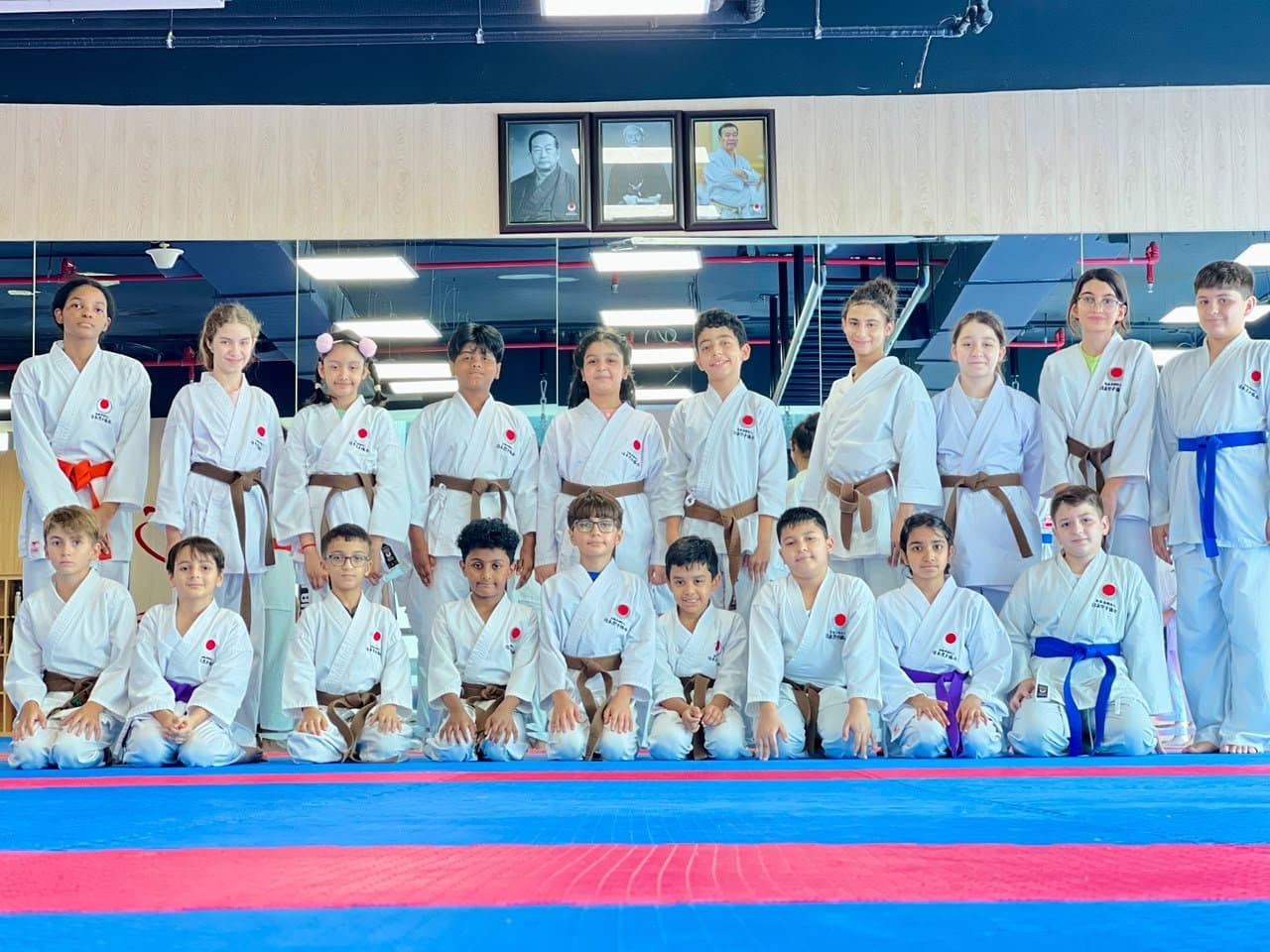Coach posing with a line of young kickboxing students holding their fists up