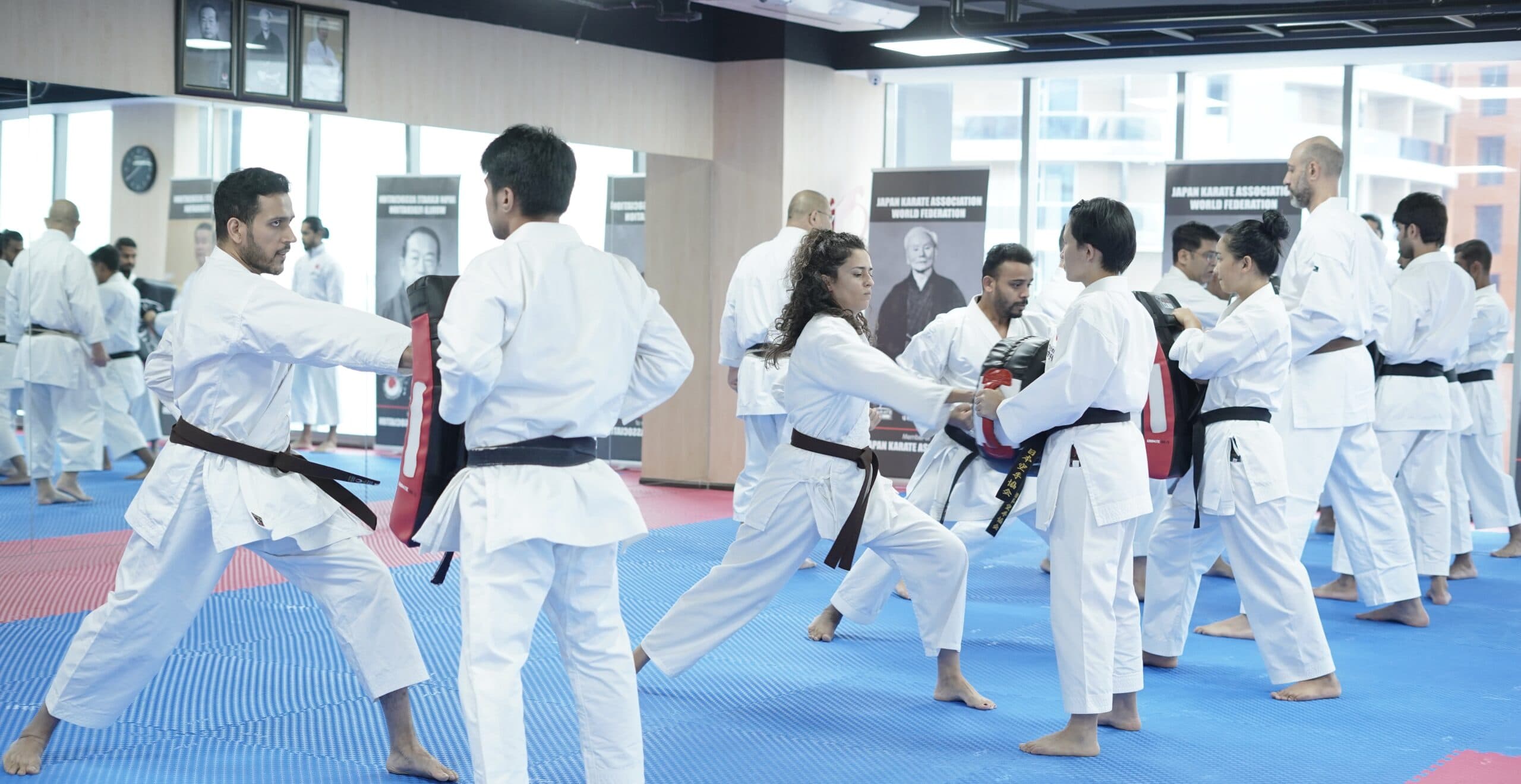 Adult students paired up practising self-defence drills on the mats