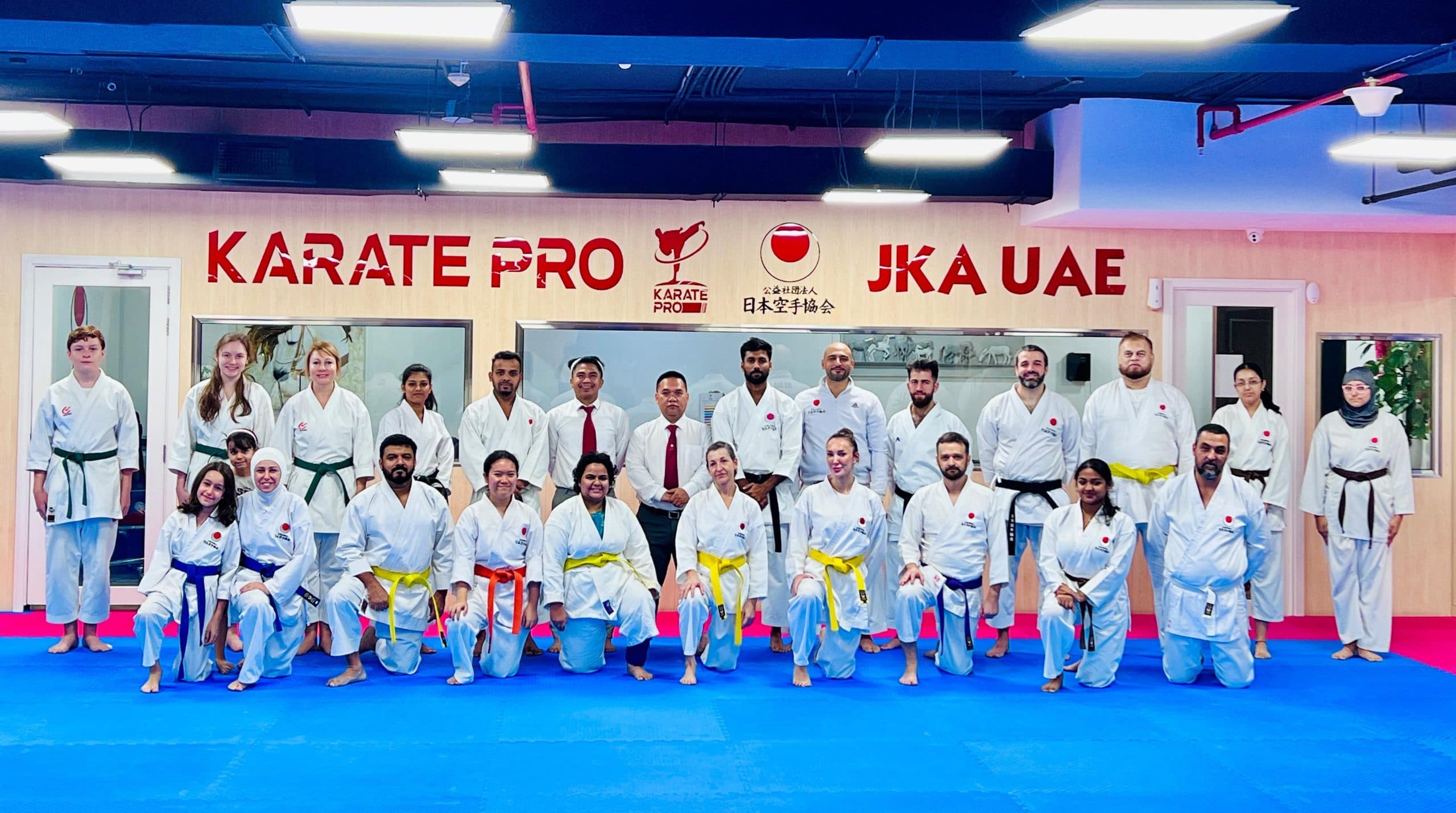 Adult karate students lined up in white gi with their instructors