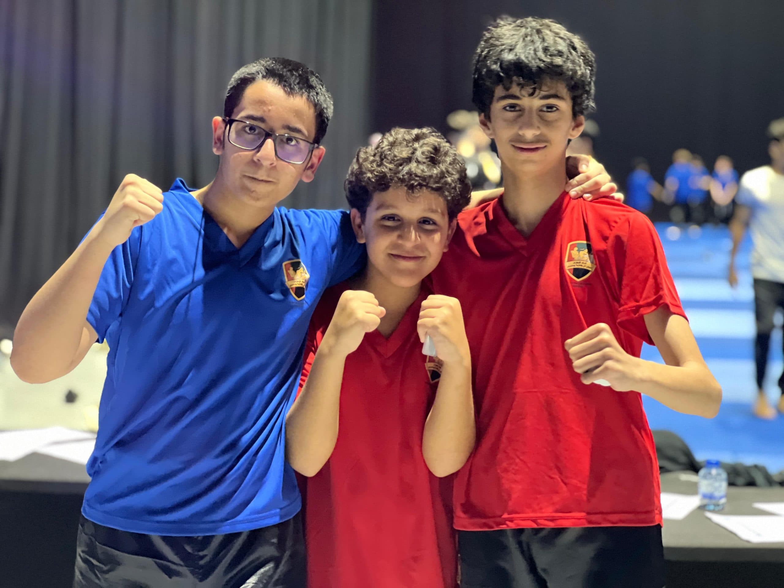 Three young kickboxing students in boxing gloves