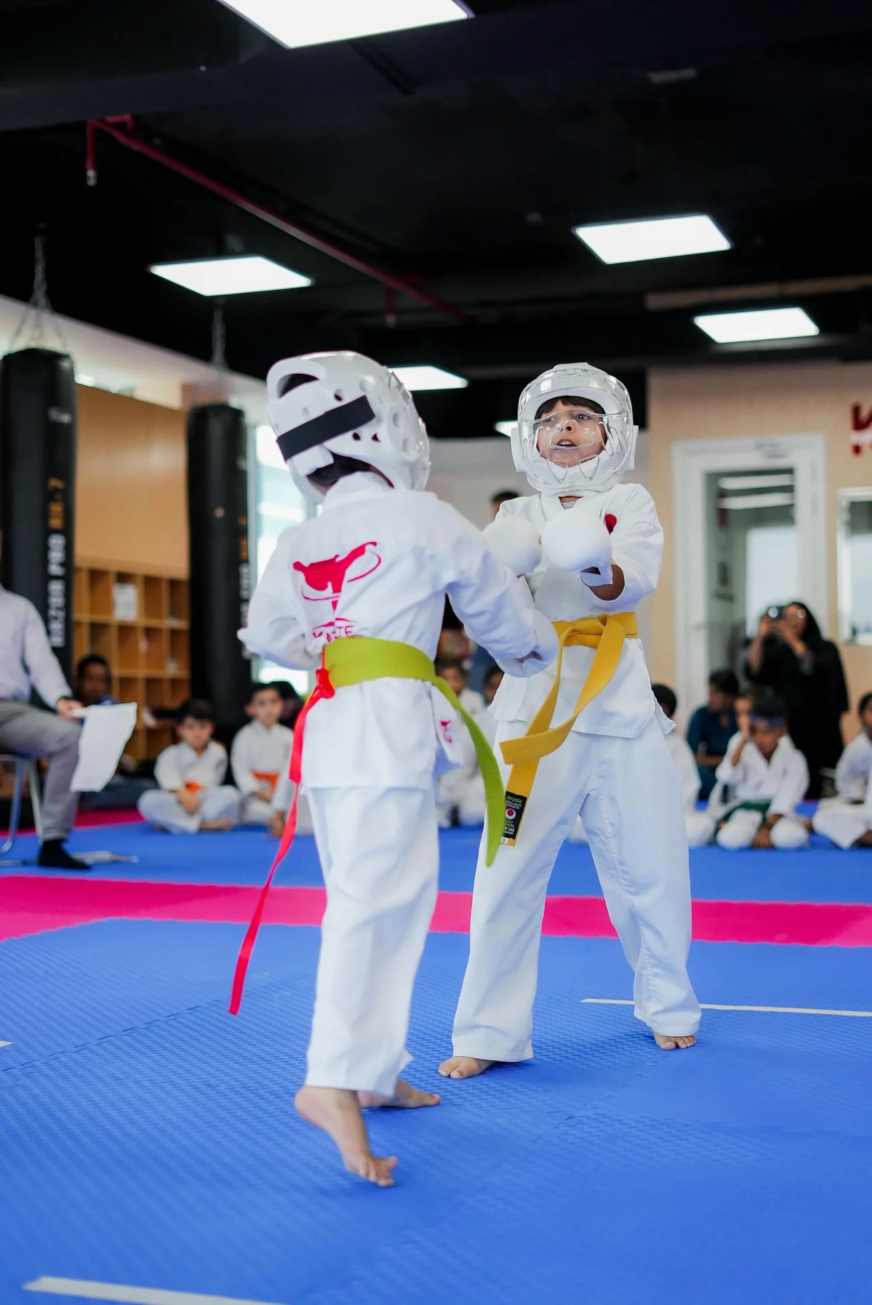 Young student in head guard practising kumite during camp