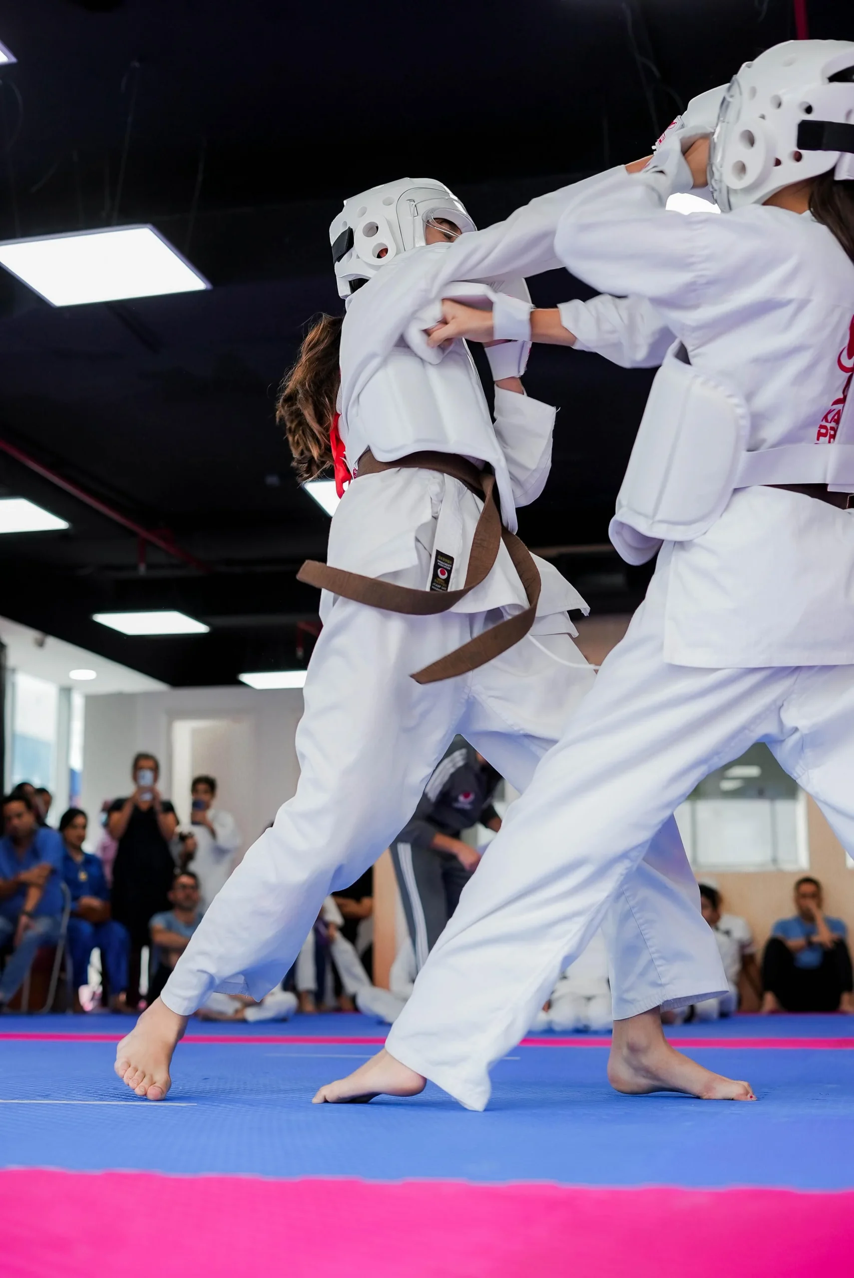 Two women in white gi practising a high kick in a ladies-only karate class