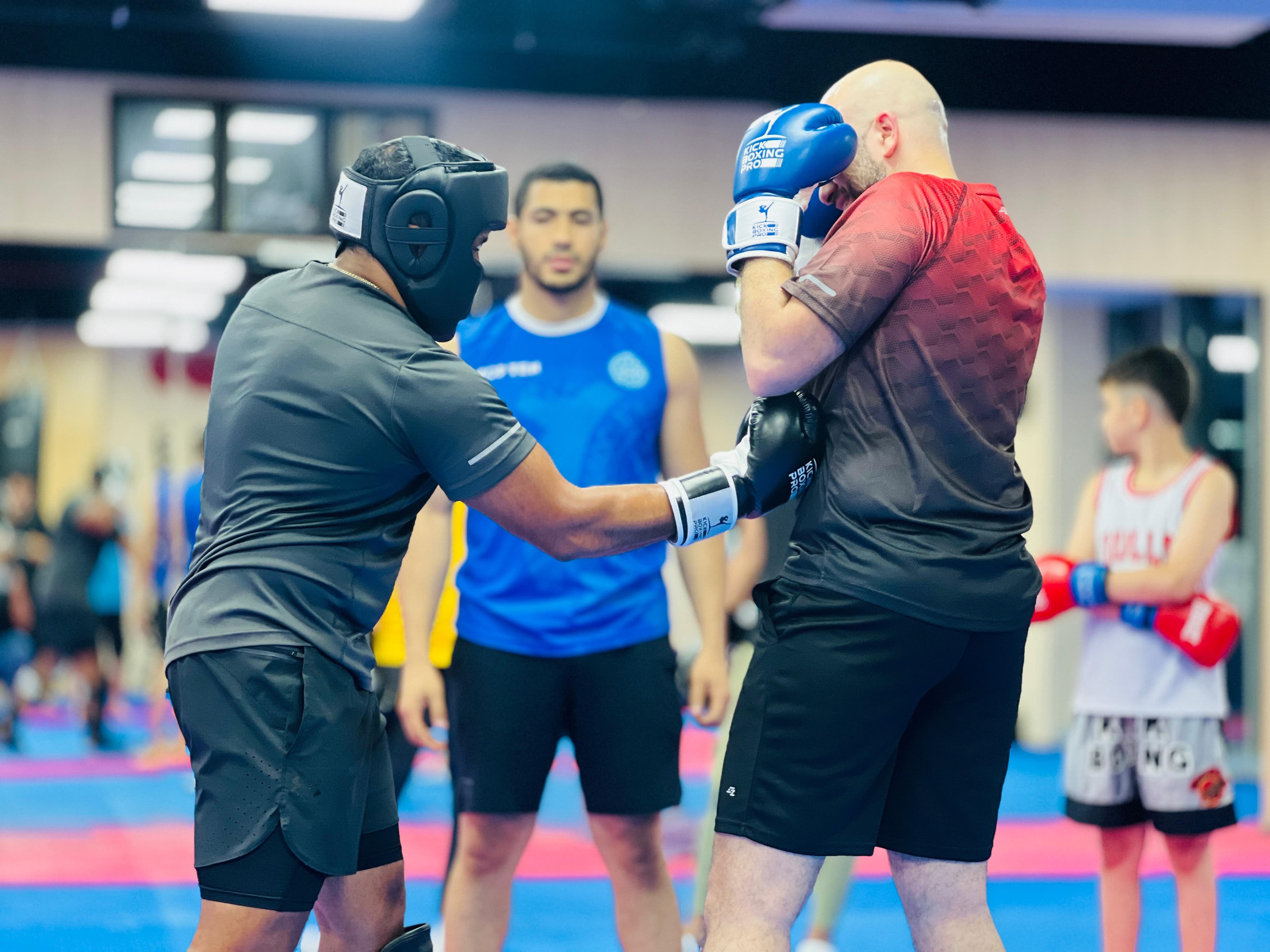 A kickboxing class working through pad drills in pairs on the dojo mats